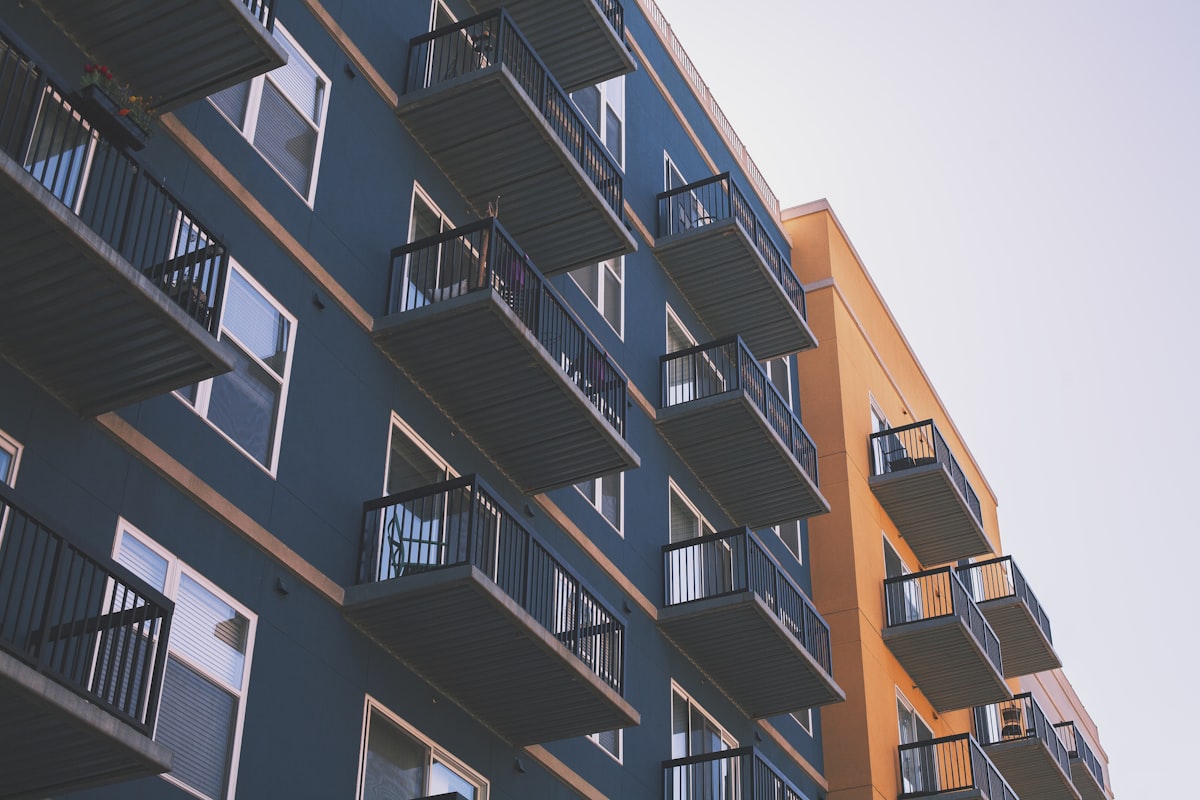 A mid-rise apartment building under flat overcast light, stacked balconies running the length of the facade.