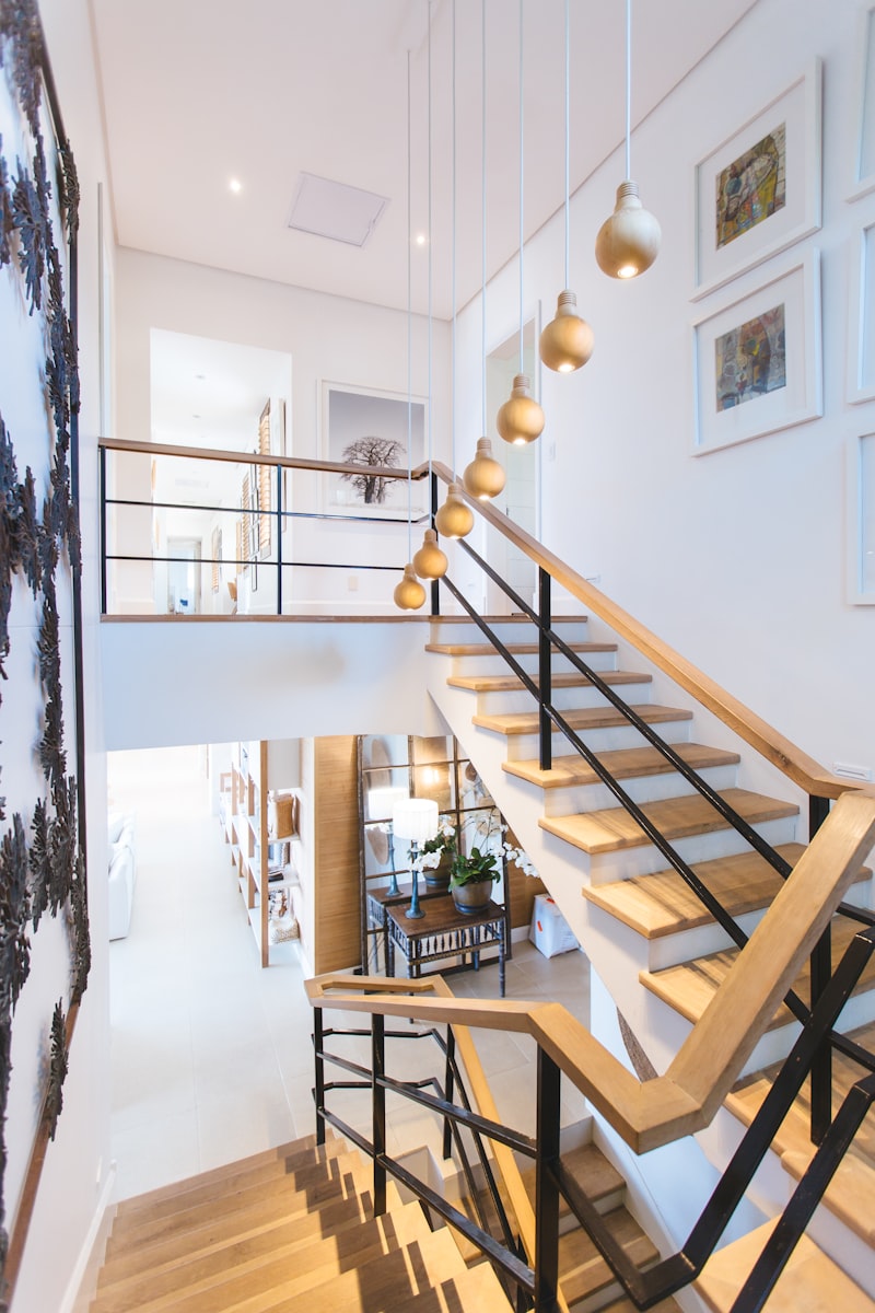 An interior stairwell shot up the run: identical treads and a straight steel handrail repeating floor after floor, the geometry receding to a small bright opening at the top.